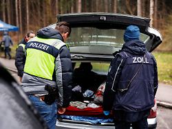ein beamter der polizei untersucht gemeinsam mit einem zollbeamten bei hofolding bayern den inhalt von einem pkw den schleierfahnder aus dem fliessenden verkehr in eine kontrollstelle gezogen haben