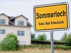 ein ortsschild mit der aufschrift sommerloch steht am ortseingang neben einem haus