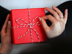 eine frau oeffnet eine mit einer schleife verzierte geschenkbox fuer sich selbst rund 2000 euro geben die bundesbuerger nach einer umfrage fuer ich geschenke aus