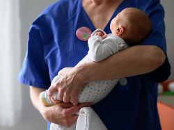 eine kinderkrankenschwester haelt ein neugeborenes nach dem wiegen auf der neugeborenenstation im drk krankenhaus chemnitz in den armen