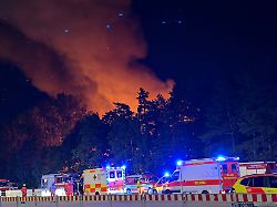 feuerwehrleute sind bei einem waldbrand im einsatz ein campingplatz und ein open air konzert in der naehe des messegelaendes seien vorsorglich geraeumt worden sagte ein polizeisprecher