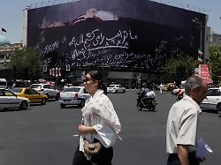 fussgaenger und autos passieren auf dem platz der islamischen revolution in der innenstadt von teheran eine werbetafel mit anti trump botschaften darunter der satz we kill trump