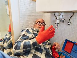 heimwerker als diy klempner mit handschuhen bei der reparatur von abfluss im bad modellfreigabe vorhanden