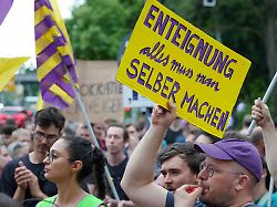 teilnehmer einer demonstration der initiative deutsche wohnen enteignen protestieren vor dem willy brandt haus unter anderem mit einem plakat enteignung alles muss man selber machen