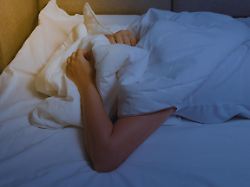 woman s hands are visible from under the covers as a symbol of fight against insomnia tired and exhausted person has nightmares