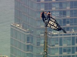zwei menschen stehen auf der spitze der antenne des empire state building und halten ein transparent hoch