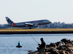 a person uses a fishing pole as a jetstar plane takes off in the background from sydney international airport in sydney australia august 6 2026