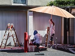 anstreicher schuetzen sich mit sonnenschirm und kopfbedeckung gegen die sonne das wetter bleibt trocken und heiss