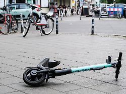 ein e scooter liegt umgekippt mitten auf einem gehweg