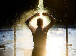 ein fruehschwimmer duscht am fruehen morgen im freibad kleefelder bad annabad im licht der aufgehenden sonne