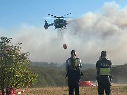 ein polizeihubschrauber mit loeschwasser aussenlastbehaelter startet zum einsatz bei den loescharbeiten beim waldbrand im huertgenwald mehrere hundert hektar waldflaeche stehen in flammen