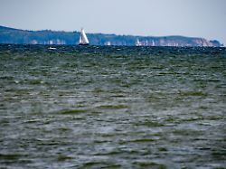 ein segelschiff faehrt auf dem greifswalder bodden vor der insel ruegen