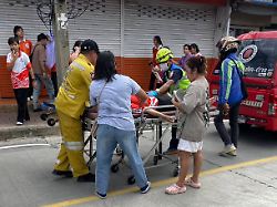 ein verletzter wird auf einer trage vor einer schule weggetragen vor der es bei einem schusswaffenvorfall in der thailaendischen provinz nonthaburi zu todesfaellen und verletzten gekommen war