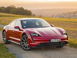 ein roter sportwagen faehrt auf einem asphaltweg durch eine laendliche landschaft porsche taycan deer carsharing
