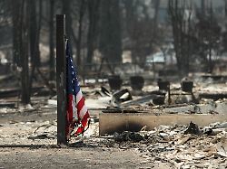 eine amerikanische flagge weht vor einem abgebrannten gebaeude in einem wohngebiet von westgate nach einem waldbrand in spokane washington