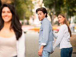 jealous girlfriend calling boyfriend distracted by other attractive woman