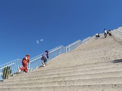 menschen erklimmen monumentale betontreppen die unter strahlend blauem himmel die renovierte pyramide von tirana hinauffuehren albanien