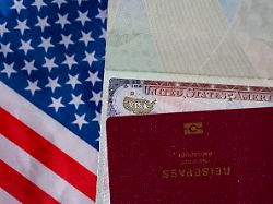 nahaufnahme eines us visums im reisepass mit amerikanischer flagge im hintergrund symbol fuer einreise immigration reisen visa antrag und internationale mobilitaet 1