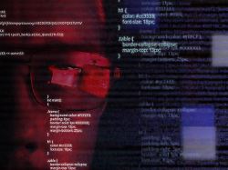programmer or hacker in glasses looking on monitor software code reflecting in the glass and flying around caucasian man face in the dark digital technologies software development red colored
