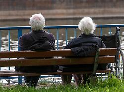 senioren sitzen auf einer parkbank am fluss rhein rollstuhl
