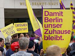 teilnehmer einer demonstration der initiative deutsche wohnen enteignen protestieren vor dem willy brandt haus unter anderem mit einem plakat damit berlin unser zuhause bleibt