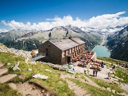 tourists have rest at olpererhutte mountain hut in zillertal in austrian alps with beautiful scenery view above lake