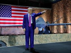 u s president donald trump gestures while delivering remarks to u s troops next to a drone and a u s flag during a visit to al udeid air base in doha qatar may 15 2025